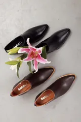 Botines de cuero negro con diseño moderno, silueta estilizada y punta fina. Cuentan con un corte en V en el lateral y tacón cuadrado de altura media.