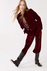 Pantalón de terciopelo color borgoña, de tiro alto, con cintura elástica en la espalda, cierre frontal, bolsillos laterales y piernas anchas.