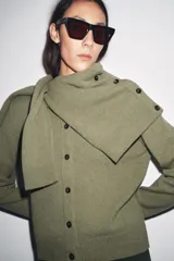 Chaqueta de tejido de punto color verde musgo, de corte cropped, con cuello redondo y cierre frontal de botones oscuros.