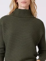 Buzo de tejido acanalado color blanco, con cuello alto y diseño de patrón en V en el frente. Presenta un corte holgado con mangas integradas sin costura de sisa.