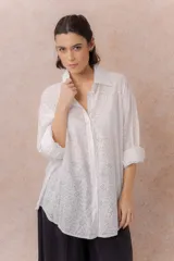 Camisa blanca oversize de algodón con bordado floral calado tipo broderie, cuello camisero clásico, mangas largas y abotonadura frontal.