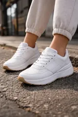 Championes urbanos de diseño moderno, color blanco con suela de goma en tono caramelo. Presentan cordones al tono y detalles perforados en la puntera.