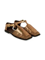 Sandalias planas color dorado metalizado, con diseño de tiras cruzadas y entramadas en el empeine, puntera cuadrada y tira ajustable con hebilla en el tobillo.