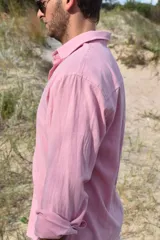 Camisa rosa de manga larga con cuello clásico y cierre abotonado.