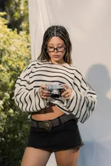 Sweater de tejido ligero a rayas horizontales blancas y negras, con cuello redondo y mangas largas. Presenta un pequeño bordado en la manga.