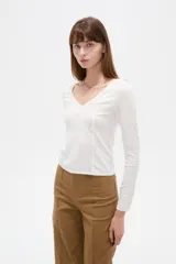 Remera negra de manga larga y calce al cuerpo, confeccionada en poliéster con diseño calado y escote en V.