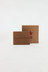 Billetera combinada en cuero marrón con costuras decorativas y pequeño aplique metálico de estrella y líneas en el frente. Interior con compartimentos y forro de algodón.