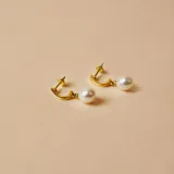 Medio aro de oro 18k con perla de cultivo colgante. Diseño minimalista y elegante.
