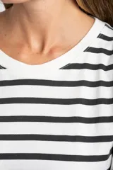 Remera de corte oversize confeccionada en algodón lavado, con diseño de rayas horizontales en color negro sobre fondo crudo, cuello redondo y mangas cortas.