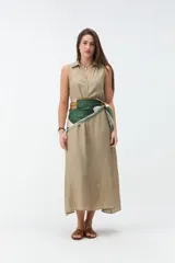 Vestido largo sin mangas de color celeste, con cuello camisero, cierre frontal con botones y bolsillos laterales.