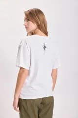 Remera blanca de algodón con cuello redondo y mangas cortas. Presenta un estampado de estrella en el frente.