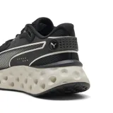 Championes Puma Softride Frequence, color negro con detalles en color arena. Presentan una suela con diseño alveolar distintivo y el logo de la marca en el lateral y la lengüeta.