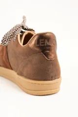 Zapatillas urbanas de cuero color marrón, con cordones estampados en tonos marrones y blancos, y suela de goma al tono. Presentan una franja lateral de gamuza y detalles con la marca en dorado.