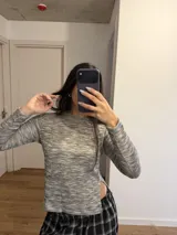 Remera de manga larga en tejido de punto jaspeado color gris, con cuello redondo y diseño con tajo lateral pronunciado.