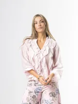 Camisa de organdí rosa pastel con finas rayas verticales metalizadas, escote en V con volados frontales y mangas largas abullonadas con puños elásticos.