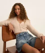 Cardigan cropped color beige con manga larga, escote en V y cierre con botones. Tejido de punto con textura ondulada y pelitos. Marca Blue Steel.