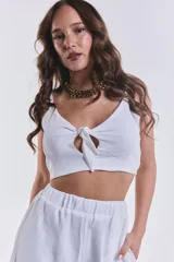 Top blanco corto con tirantes finos regulables, escote en V y detalle de nudo frontal con apertura tipo lágrima.