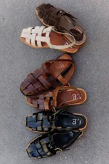 Sandalias tipo huarache de cuero con diseño de tiras entrelazadas, punta cerrada y cierre con hebilla lateral. Cuentan con suela plana y plantilla con logo grabado.