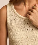 Vestido midi color crema, tejido en punto texturizado, sin mangas y con cuello redondo.