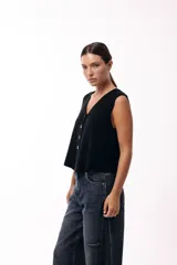 Chaleco tejido de punto con escote en V y cierre frontal con botones. Presenta una silueta recta y un diseño minimalista.