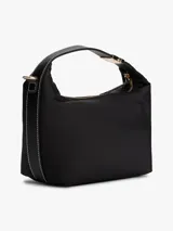 Cartera tipo hobo de Tommy Hilfiger confeccionada en nailon brillante color negro. Presenta un diseño minimalista con el monograma TH metálico en dorado en la parte frontal, cierre superior con cremallera, asa superior fija y correa cruzada extraíble con detalles en contraste.