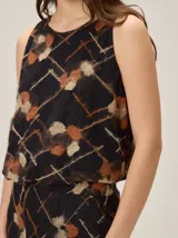 Top negro sin mangas con estampado geométrico y manchas texturizadas en tonos marrones y beige, con silueta balloon.
