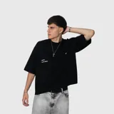 Remera negra de corte oversize con mangas cortas amplias y cuello redondo. Presenta un pequeño estampado minimalista en color blanco en el pecho.