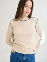 Polera de manga larga confeccionada en tela rib color bordó, con cuello alto y hombreras. Presenta costuras a la vista con pespuntes en hilo de color contrastante en el cuello, puños, hombros y ruedo.