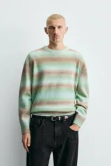 Jersey de punto con ajuste relajado, cuello redondo y manga larga. Presenta un diseño de rayas horizontales difuminadas en tonos verde agua y marrón, con acabados en rib en cuello, puños y ruedo.