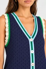 Vestido corto azul marino de tejido abierto, con escote en V, cierre frontal de botones y detalles de ribetes en celeste y verde, con terminaciones en encaje crudo.