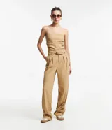 Pantalón de vestir color beige, de corte recto, con cintura alta, trabillas y cinturón cruzado. Presenta pliegues delanteros y bolsillos laterales.