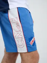 Short de baño de secado rápido, color azul, con cordón ajustable en la cintura, bolsillos laterales y el escudo del Club Nacional de Football junto al logo de Umbro bordados en las piernas.
