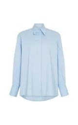Camisa de corte oversize color celeste, con cuello clásico, cierre frontal de botones y mangas largas con puños abotonados.