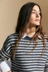 Sweater de punto con diseño de rayas horizontales en tonos tierra, con textura acanalada y cuello redondo. Presenta un corte relajado y mangas largas.