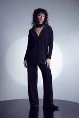 Mono largo de punto color gris oscuro con lurex, escote en V y cierre frontal con un botón. El pantalón es de corte palazzo.