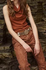 Pantalón de cuero color marrón con estampado abstracto, corte acampanado y abertura en el ruedo.