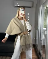 Poncho de tejido suave color blanco, con diseño abierto y flecos en el ruedo inferior.