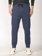 Pantalón de jogging color verde militar, corte slim, con puños elastizados en los tobillos y cordón ajustable en la cintura. Presenta un bolsillo lateral con cierre.