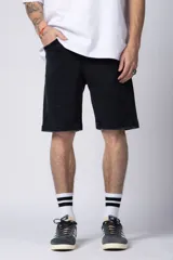 Bermuda de jean color negro lavado, de corte regular y largo a la rodilla, con dobladillo doblado en el ruedo.