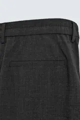 Pantalón negro de corte ancho con pliegues frontales dobles, bolsillos delanteros y traseros de vivo. Cierre frontal con cremallera y botón.