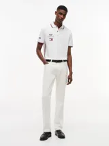 Chomba de corte regular confeccionada en algodón elástico, con cuello polo y cartera de dos botones. Presenta ribetes distintivos en cuello y puños, cinta lateral y múltiples logos bordados que incluyen Tommy Hilfiger, Cadillac Formula 1 Team y Pirelli.