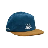 Gorra tipo snapback de corderoy, con corona azul y visera plana color tostado. Presenta un bordado frontal con diseño de sol y el logo de la marca bordado en el lateral.