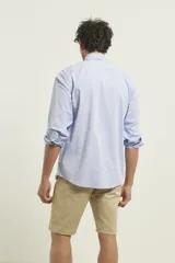 Camisa celeste de algodón con cuello abotonado, manga larga con puños abotonados y bolsillo en el pecho. Corte clásico.