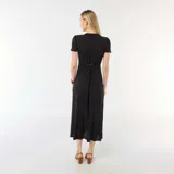 Vestido midi negro con estampado de lunares blancos, escote en V, mangas cortas y botones frontales.