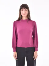 Polera color fucsia de mangas largas abullonadas y cuello alto.