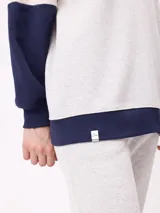 Sweater estilo rugby de Rusty, con diseño color block en tonos bordó, azul marino y verde. Presenta cuello polo en color crema con cierre frontal de botones, mangas largas con puños elásticos y logo de la marca bordado en el pecho.