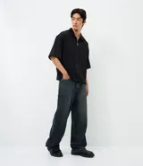 Pantalón jean masculino de corte super baggy, confeccionado en denim de algodón. Presenta un acabado liso y un detalle de estrella aplicado en el bolsillo trasero.