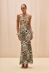 Vestido largo de crochet en tonos coral, blanco y negro, con busto cruzado, cortes estratégicos en la parte delantera y cintura, y detalles de ribete trenzado. Incluye un body interior y una falda de corte sirena.