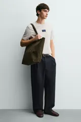 Bolso tipo shopper de piel con acabado serraje, color verde militar. Cuenta con dos asas de mano y un bolsillo interior con cierre de cremallera.