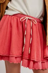 Minifalda color coral, de tela liviana con dos capas de volados, cintura elastizada con cordón ajustable y borde festoneado con puntilla.